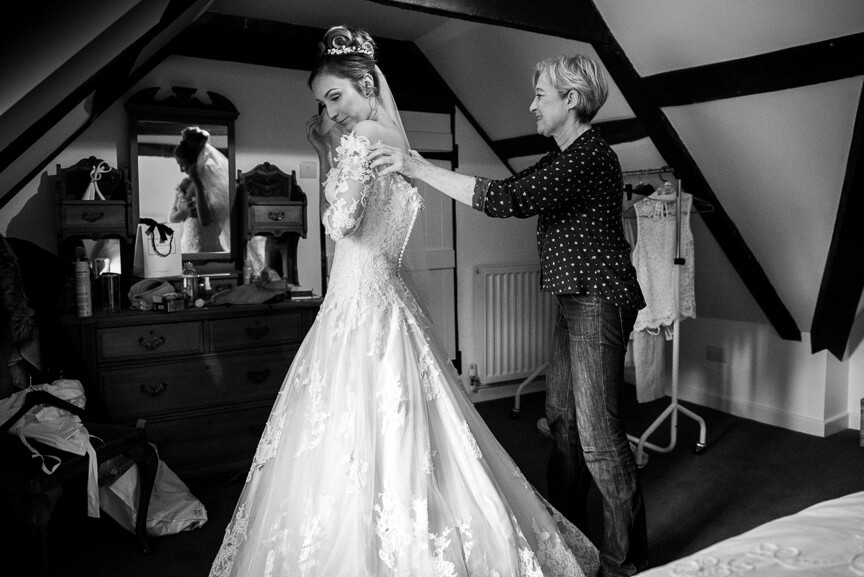 Mother of bride putting brides dress on